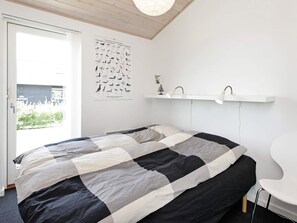 A bedroom with a bed, a poster on the wall, a window, and a door. - 5 Star Holiday Home in Haderslev (Haderslev)