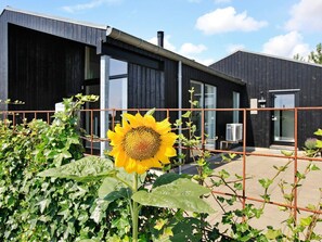 A modern building with a large sunflower in the foreground, a metal fence, and a clear sky. - 5 Star Holiday Home in Haderslev (Haderslev)