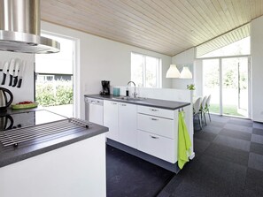 A modern kitchen with a central island, a coffee machine, and a sink. - 5 Star Holiday Home in Haderslev (Haderslev)
