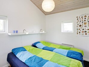 A bedroom with a bed, two bedside tables, a wall-mounted shelf, a poster, and a window. - 5 Star Holiday Home in Haderslev (Haderslev)