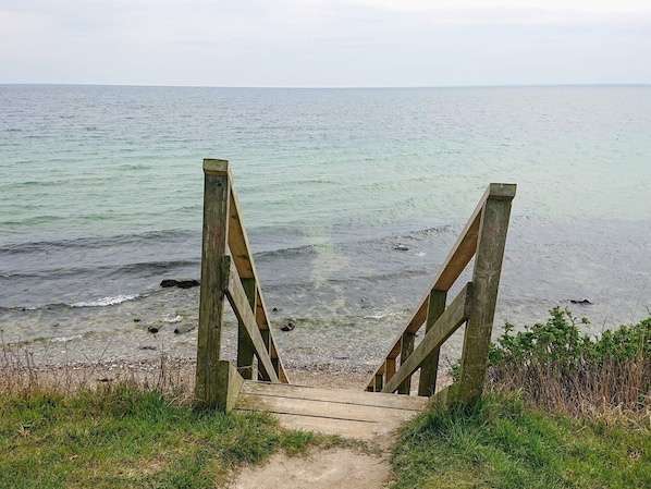 A wooden staircase leading to a beach with a view of the sea.
