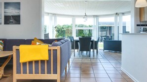 A modern living room with a sofa, a wooden chair, and a dining area with chairs and a table. - Spacious Holiday Home in Hemmet Jutland near Sea (Hemmet)