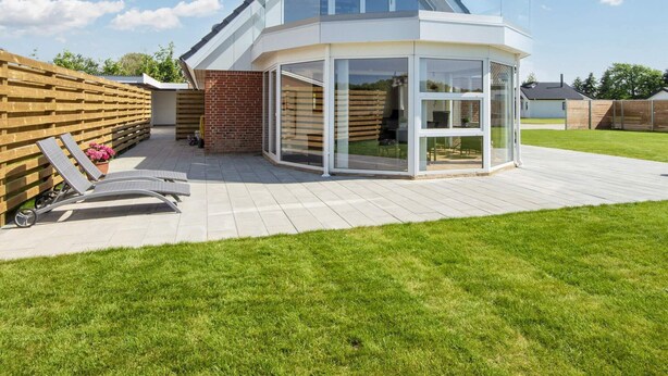 A modern house with a glass conservatory, a wooden deck, and a well-maintained lawn. - Spacious Holiday Home in Hemmet Jutland near Sea (Hemmet)