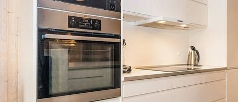 A modern kitchen with a built-in oven, a microwave, and a kettle on the countertop.