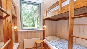 Une chambre avec un lit superposé, une fenêtre, un radiateur et un petit tabouret.