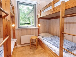 Habitación con literas, una ventana, un radiador y un taburete pequeño.