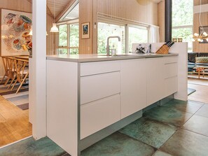 A modern kitchen with a central island, wooden flooring, and a view of the outdoors. - 4 Star Holiday Home in Hals (Hals)