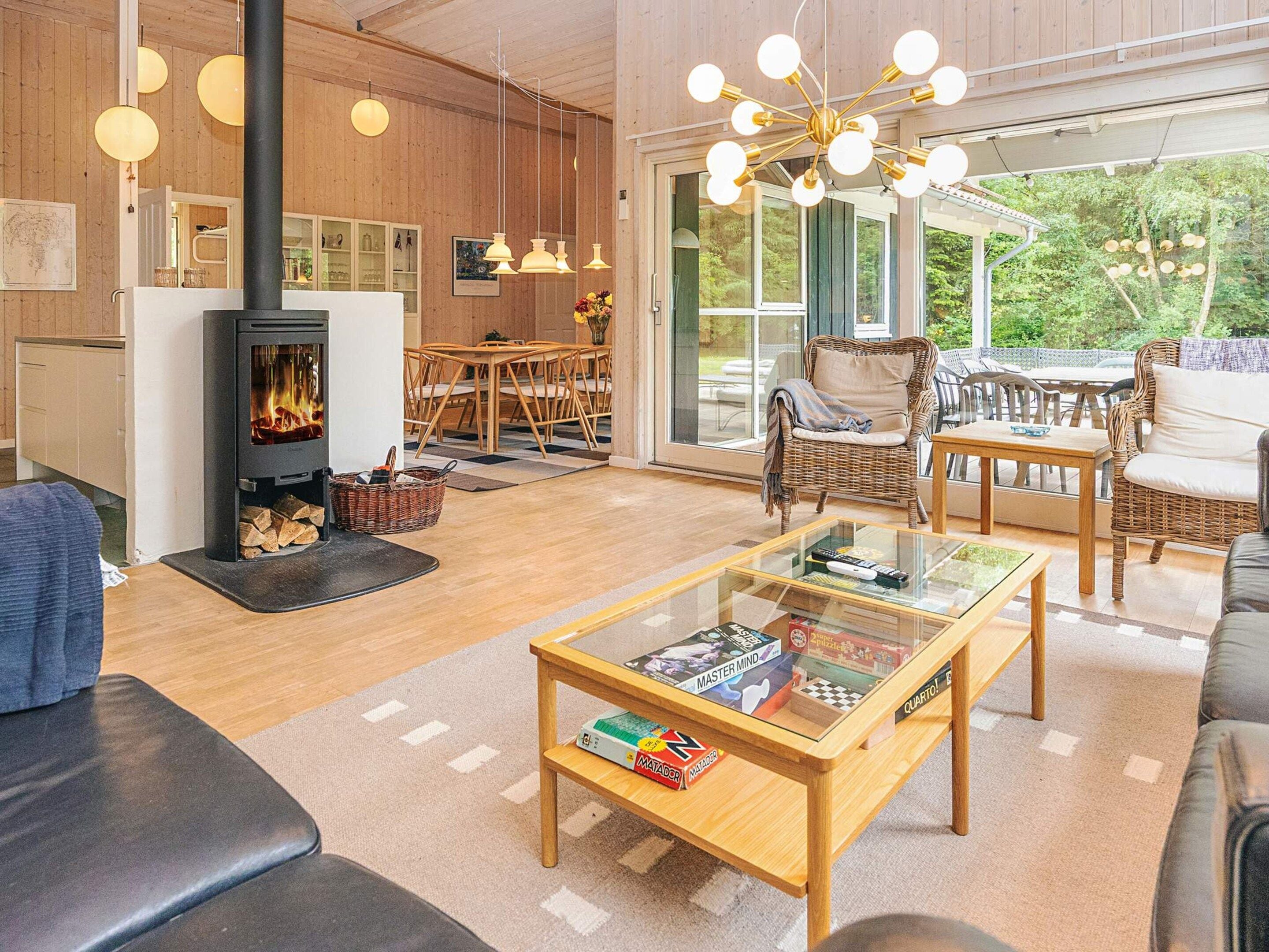 A cozy living room with a fireplace, comfortable seating, a glass coffee table, and a view of the outdoors.