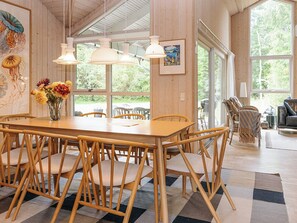 A dining area with a wooden table and chairs, pendant lights, and a vase of flowers. - 4 Star Holiday Home in Hals (Hals)