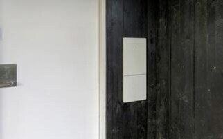 Una puerta con un panel blanco y un objeto rectangular pequeño sobre él.