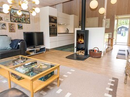 Una sala de estar moderna con televisor, chimenea, pisos de madera y una mesa de centro de vidrio.
