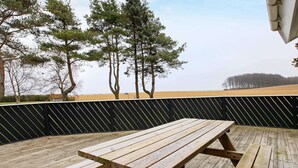 Une terrasse en bois avec des tables de pique-nique et une clôture noire.