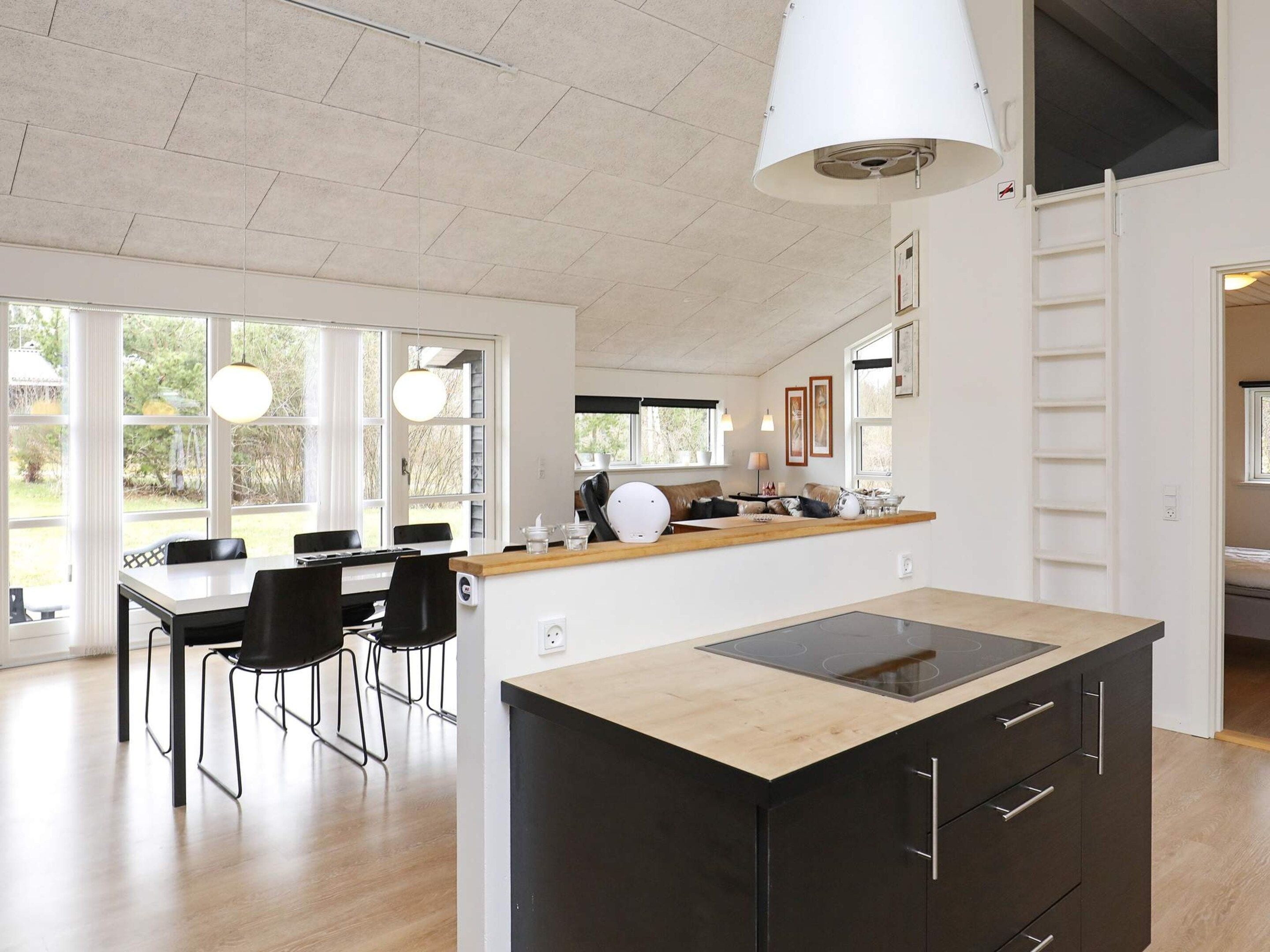 Een moderne keuken met een centraal eiland, zwarte kastjes en een houten aanrechtblad.