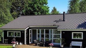 Moderni talo, jossa on tumma julkisivu, suuret ikkunat ja laatoitettu katto.