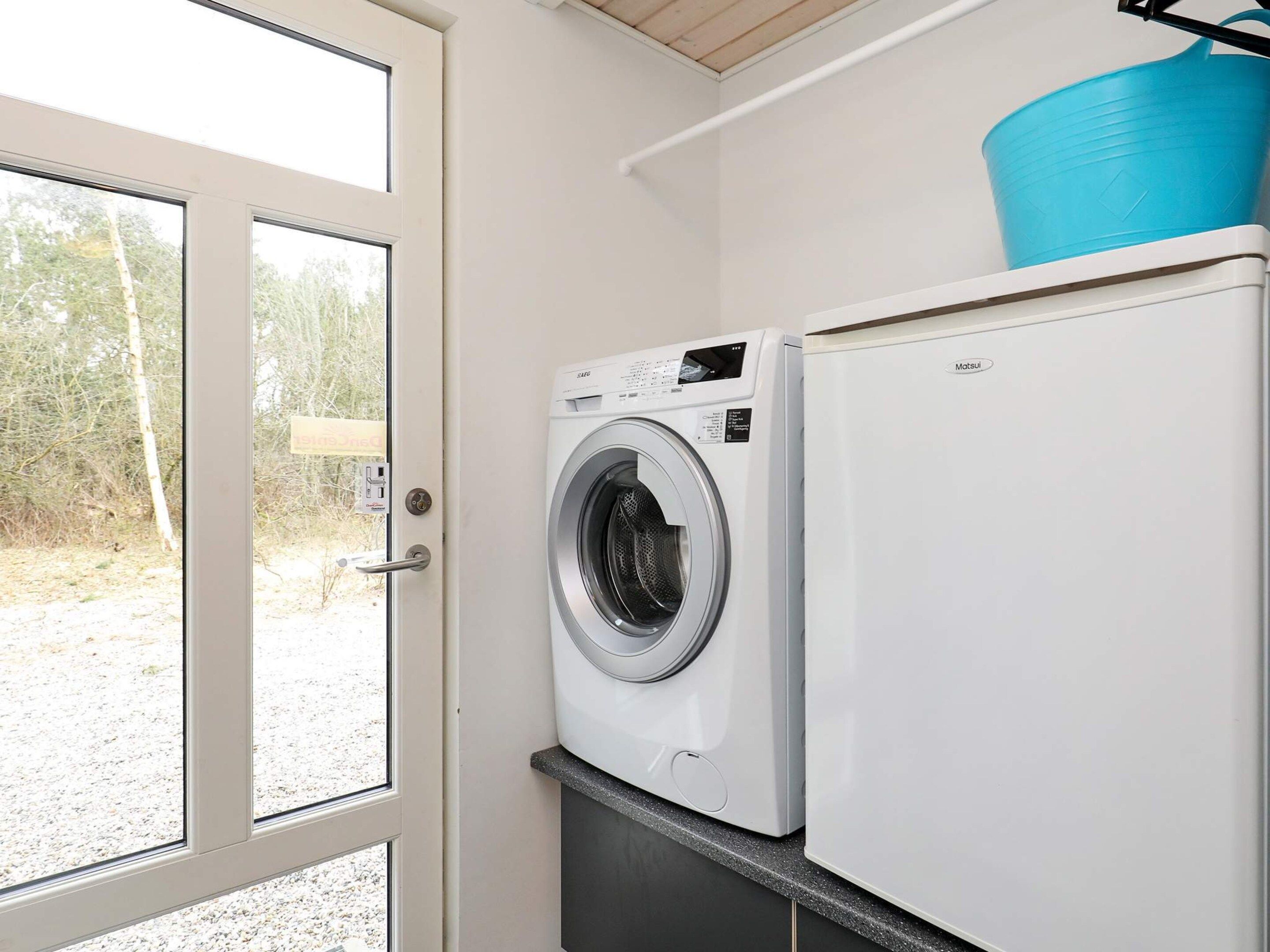Un área de lavandería con lavadora y refrigerador.