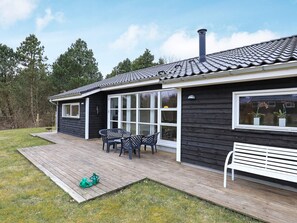 A house with a deck, outdoor seating, and a chimney.