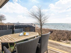 Una terraza de madera con una mesa y sillas con vistas a la playa.
