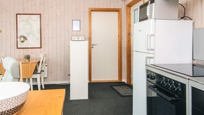 Cocina compacta con microondas, estufa y refrigerador. Hay un comedor con mesa y sillas.