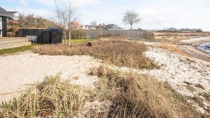 Una playa arenosa con una cerca de madera y un banco.