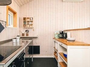 Eine kleine Küche mit Holzwänden, einem eingebauten Herd und einer Kaffeemaschine.