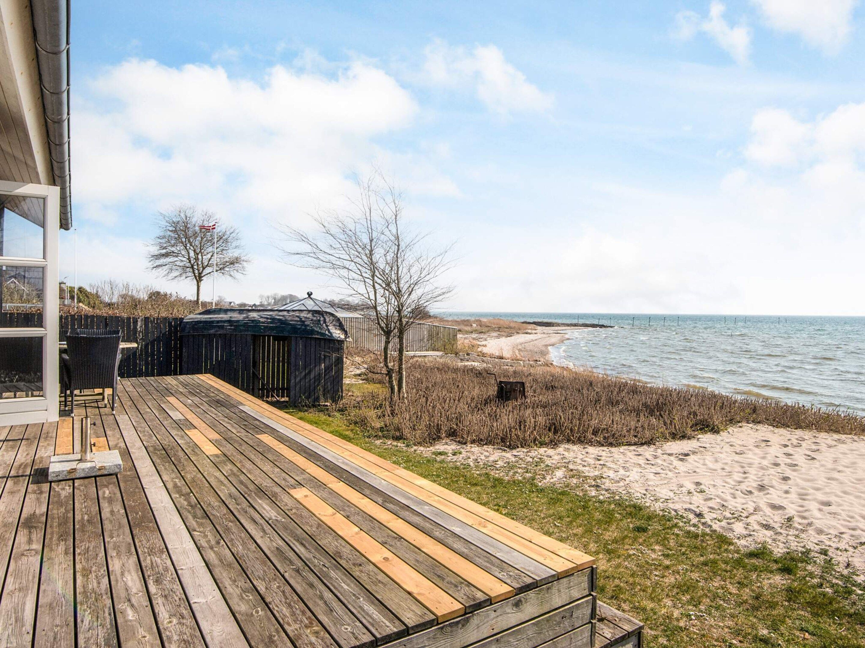 A wooden deck with a view of the beach and ocean.
