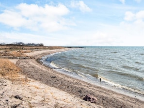 Un paisaje costero con una playa arenosa, mar tranquilo y cielo despejado.