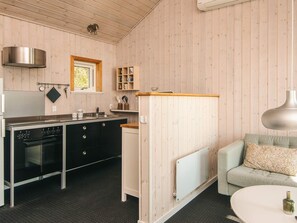A compact kitchen with a stove, sink, and wooden cabinets. - 4 Star Holiday Home in Bjert (Bjert)