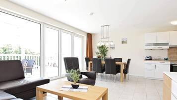 Eine moderne Wohnung mit Essbereich, Küche und einem Balkon mit Gartenmöbeln.