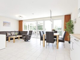 A modern living room with a sofa, coffee table, and dining area with chairs and a table.