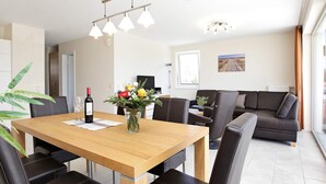 A modern dining area with a wooden table, black leather chairs, and a vase of flowers. - Holiday Home in GroÃŸenbrode (Grossenbrode)