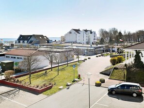 A parking area with a car, a building with a sloped roof, and a clear sky.