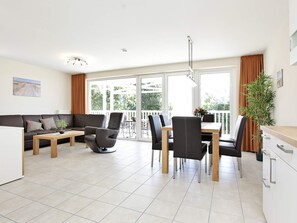 A modern living room with a sofa, coffee table, and dining area with chairs and a table.