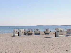 Beach chairs with numbers on them, arranged on a sandy beach with the sea in the background.