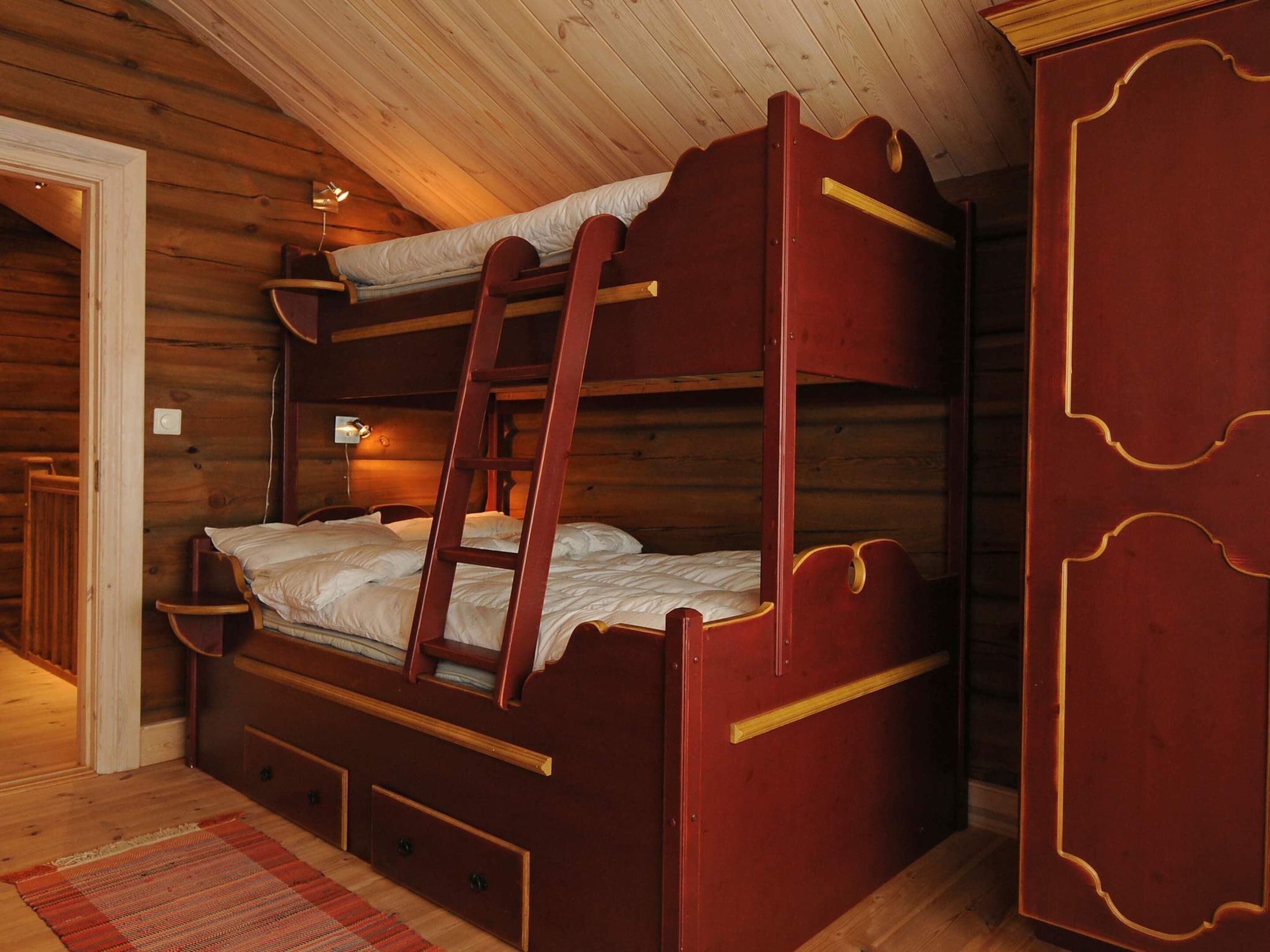A wooden bunk bed with a ladder, a small bedside table, and a nightstand.