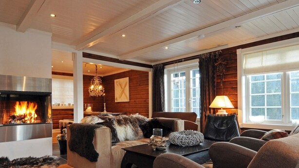 A cozy living room with a fireplace, wooden walls, and a comfortable seating area. - Holiday Home in FÃ¥vang (Ringebu)