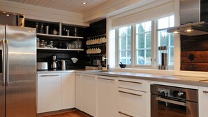A modern kitchen with stainless steel appliances, white cabinetry, and a large window providing natural light. - Holiday Home in FÃ¥vang (Ringebu)