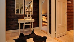 A room with a wooden wall, a white door, a white chair, and a black and white cowhide rug. - Holiday Home in FÃ¥vang (Ringebu)