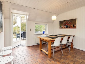 A dining area with a wooden table, white chairs, and a painting of flowers on the wall. - 8 Person Holiday Home in Blavand-by Traum (Blavand)