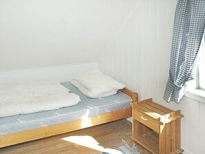A small, single-bed room with a wooden headboard, a small wooden nightstand, and a window with a checkered curtain. - Holiday Home in Vevang (Hustadvika)