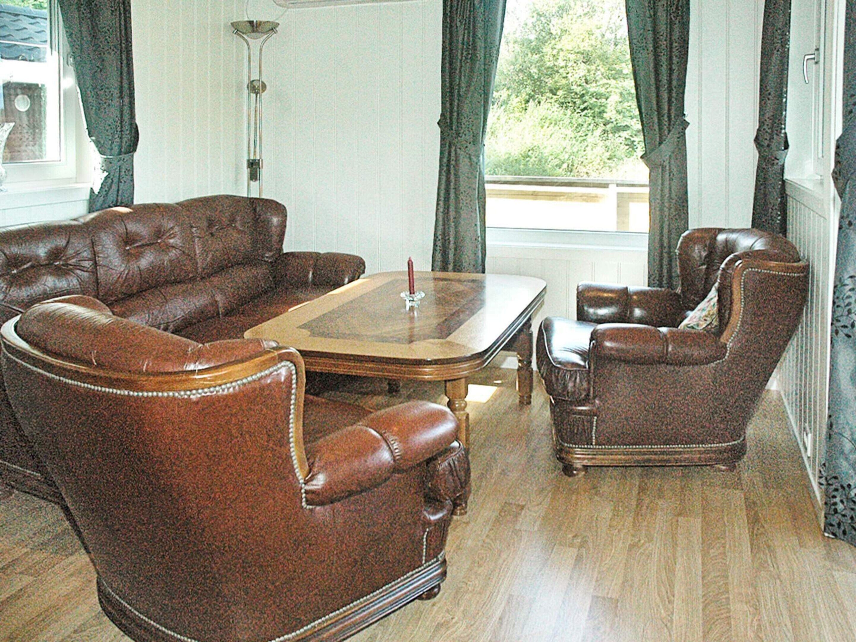 A living room with a brown leather sofa, a matching armchair, and a wooden coffee table.