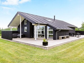 A modern house with a sloped roof, a covered patio, and a large window.