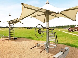 Outdoor exercise equipment with a shaded area, a seesaw, and a swing set. - 5 Star Holiday Home in Brovst (Brovst)