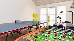 A room with a ping pong table, a foosball table, and a treadmill. - 5 Star Holiday Home in Brovst (Brovst)