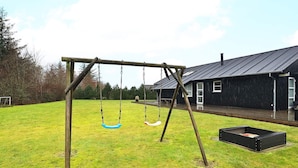 A wooden swing set in a grassy yard with a house in the background. - 5 Star Holiday Home in Brovst (Brovst)
