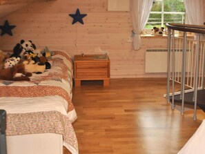 A cozy room with a wooden floor, a bed with a floral bedspread, a nightstand, and a window with curtains. - Holiday Home in Mariestad (Mariestad)
