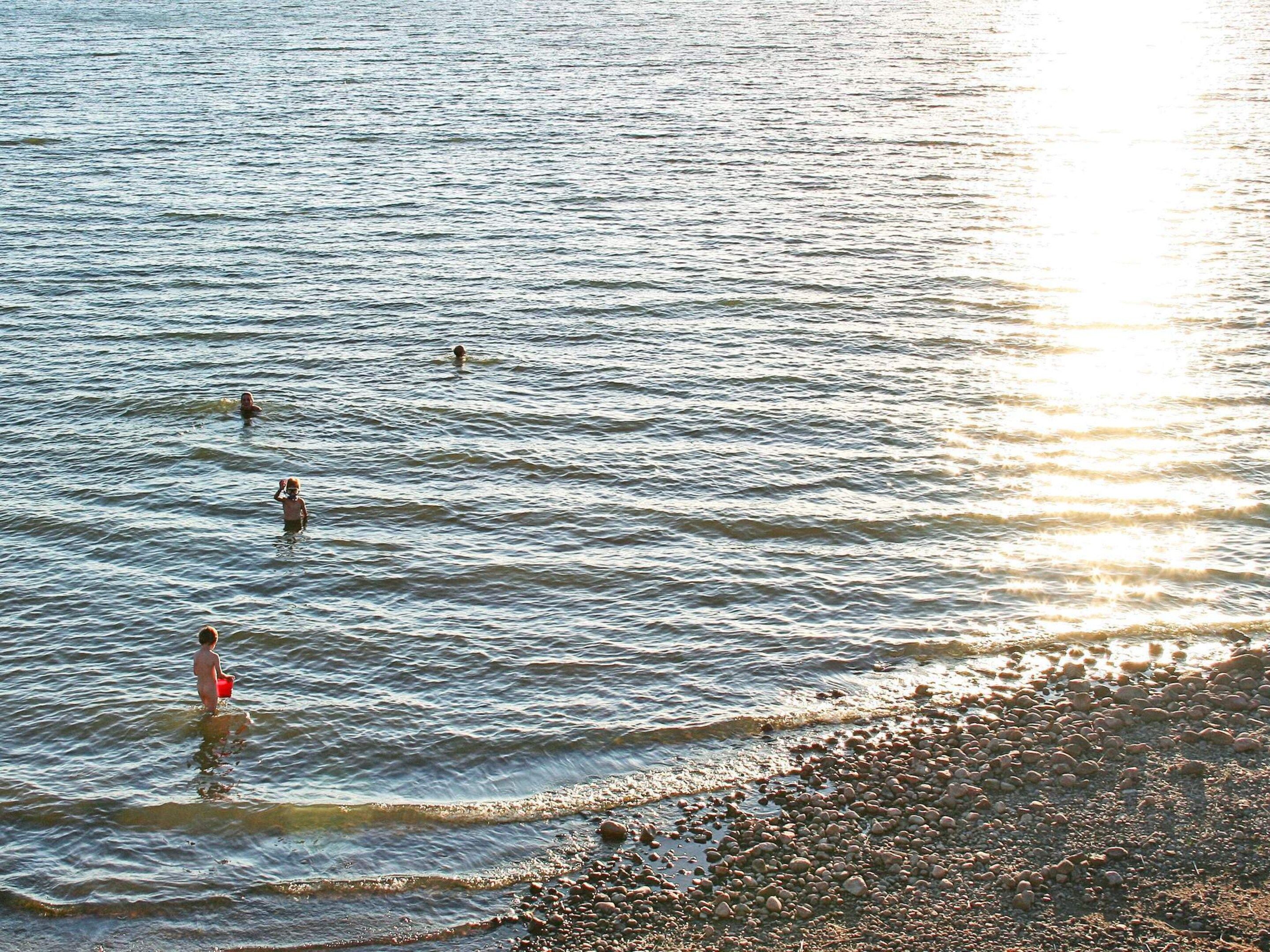 A beach with calm water and a pebbly shore.