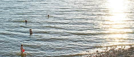 A beach with calm water and a pebbly shore.