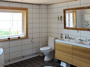 A bathroom with a toilet, sink, and mirror. - Holiday Home in Mariestad (Mariestad)