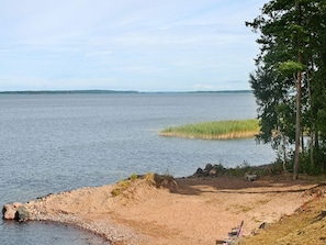 A beach with a rocky shoreline, a bench, and a view of the water. - Holiday Home in Mariestad (Mariestad)