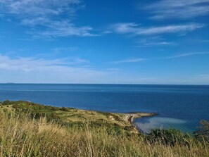 Eine Küstenlandschaft mit klarem Himmel, grasbewachsenem Gelände und Blick aufs Meer.